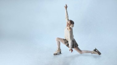 Genç bayan buz patencisi, ekose etek ve süveterle zarifçe esniyor. Gençlik enerjisi kavramı, rahatlamış farkındalık, kış hareketi boyunca kendini ifade etme ve kadınsı denge..
