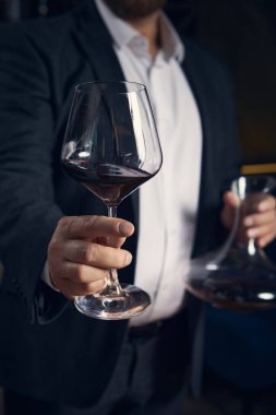 Sommelier kendine güvenerek bir bardak kırmızı şarap sunuyor. Konukseverlik kavramı, farkındalık ve lüks hizmetlerde duygusal sıcaklıkla arıtılmış iletişim..