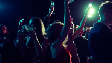 Geceyarısı yeni yıl kutlaması, dans eden ve kadeh kaldıran insanlarla. Gece hayatı reklamcılığı, neşeli alkol markalaşması, dijital kutlama ve duygusal birlik kavramı.