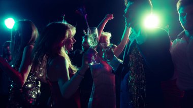 Arkadaşların dans ettiği ve kadeh tokuşturduğu neşeli bir Noel gecesi. Tatil kampanyası görselleri, etkinlik pazarlaması, parti modası ve gençlik enerjisi kavramı