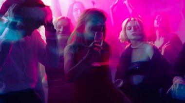 Yeni yıl kutlamaları şampanyayla ve pembe ışık altında renkli hareket bulanıklığıyla. Modern gece hayatı kavramı, duygusal neşe ve şenlikli markalaşma.