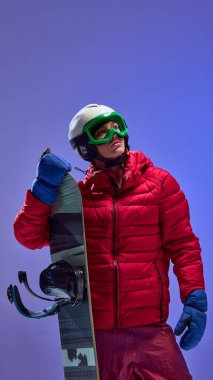Kırmızı ceketli ve miğferli snowboardcu stüdyo ışığı altında yukarı bakıyor. Arzu, hazırlık, spor markalaşması, tasarım kampanyaları ve motivasyon görselleri kavramı.