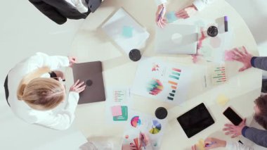 Çizelgeler, dizüstü bilgisayarlar ve yuvarlak masa üzerine yapışkan notlarla yapılan iş toplantılarına bakış açısı. Takım çalışması, veri güdümlü yönetim, fikir üretimi ve analitik işbirliği kavramı.