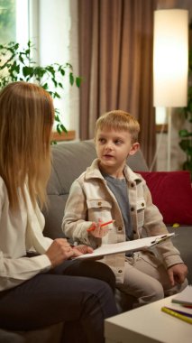 Çocuk psikoloğu terapi sırasında çocuğu dinliyor. Gelişim psikolojisi, iletişim becerileri, eğitim programları ve sosyal kampanyalar kavramı.