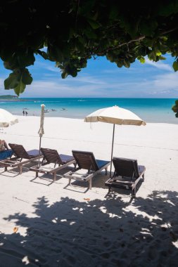 Plaj tropikal adada. Açık mavi su, kum ve bulutlar. plaj yataklar ve şemsiye