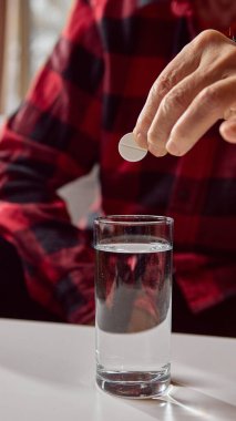 Son sınıf öğrencisi çözünmeden önce tableti su bardağının üstünde tutuyor. Eczacılık eğitimi, evde tedavi eğitimi ve sağlık bilinci kavramı.