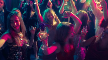 Gülümseyen insanlarla dolu neşeli Noel dans pisti ve şampanya. Tatil markaları, gece hayatı reklamları, moda kutlamaları ve duygusal enerji kavramı.