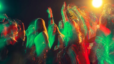 Yeni yıl dansçıları coşkuyla kırmızı ve yeşil lazer ışıklarının arasından geçiyorlar. Gece hayatı görselleri, enerjik markalaşma, kutlama reklamcılığı ve gençlik duyguları kavramı.