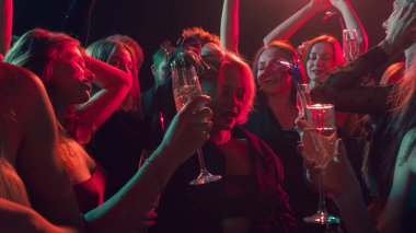 Noel gecesi dans partisinde gülümseyen yüzler kırmızı parlıyor. Etkinlik pazarlama, duygusal birlik, gece hayatı eğlencesi ve modern eğlence kavramı