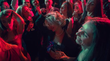 Kırmızı ışıkta kalabalık dansı ve şampanya eşliğinde neşeli bir yeni yıl kutlaması. Gece hayatı reklamcılığı, şenlikli duygular ve genç seyirciler için eğlence markası kavramı