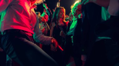 Noel partisinde dans eden kalabalık şampanya ve parlak kırmızı-yeşil ışıklarla. Şenlikli gece hayatı kutlaması, sosyal neşe ve modern etkinlik tanıtımı kavramı