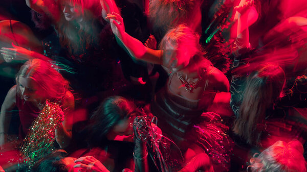 Red and gold lights illuminate dancers in New Year night celebration. Concept of nightlife advertising, emotional movement, and modern party visuals