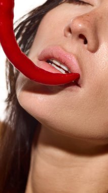 Gözleri kapalı bir kadın yüzü ve parlak ışıkta dudaklarında kırmızı biber. Reklam baskı ambalajı, cilt bakımı, sağlık kişisel bakım ve sanat editörü kavramı..