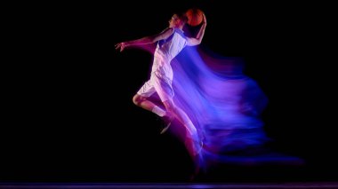 Basketbol atleti parlak mor ışık yollarıyla güçlü bir atlayış yapıyor. Güç kavramı, vücut kontrolü, spor terfisi ve modern atletizm gelişimi.