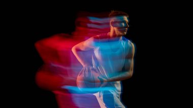 Basketbolcu topu kırmızı ve mavi neon ışıkla hareket halinde tutuyor. Fitness eğitimi, spor liderliği, atletik tasarım ve takım koordinasyonu kavramı.