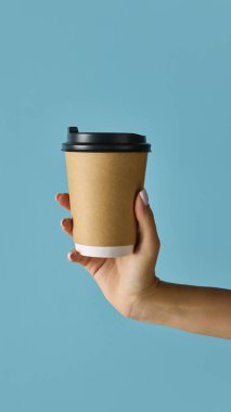 Kahverengi kraft kağıdından yapılmış, mavi kapaklı kahve fincanı. Sürdürülebilir kafe ambalajı, içecek ürün tasarımı ve restoran pazarlama için model kavramı.