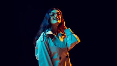 Gözlüklü bir kadın kulaklıkla gülümseyip renkli bir ışıkla müzik dinliyor. Müzik endüstrisi kavramı görsel, sosyal medya içeriği, duygusal refah ve yaşam tarzı ifadesi.