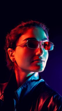 Yansıtıcı gözlüklü bir kadın karışık kırmızı ve siyan ışıkta yukarı bakıyor. Marka fotoğrafçılığı, duygusal ifade, yaratıcı tasarım ve iyimserlik yoluyla esinlenme kavramı.