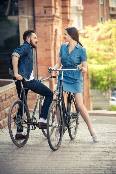 Young couple sitting on a bicycle opposite the city