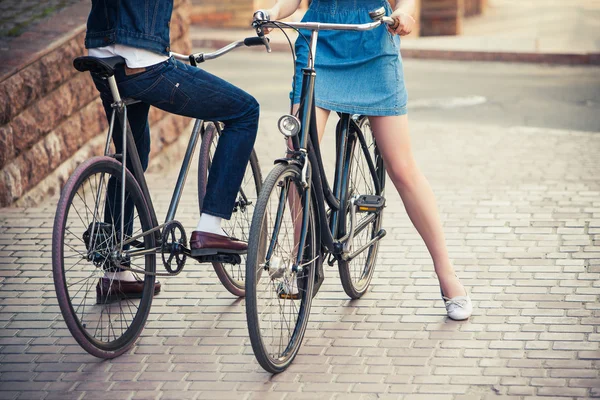 Jong koppel zittend op een fiets tegenover de stad — Stockfoto