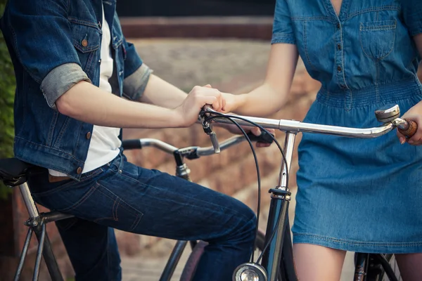 Junges Paar sitzt auf einem Fahrrad gegenüber der Stadt — Stockfoto