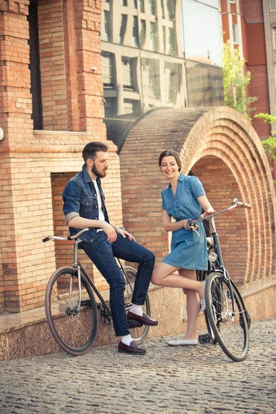 Νεαρό ζευγάρι που κάθεται σε ένα ποδήλατο απέναντι από την πόλη — Φωτογραφία Αρχείου