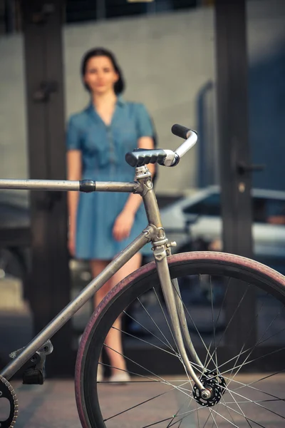 Młoda dziewczyna z rower naprzeciwko miasta — Zdjęcie stockowe
