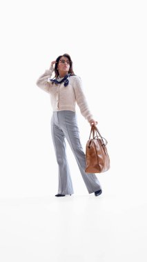 El çantası ve atkıyla poz veren iş kadını kendine güvenen şık bir modda. Yaşam tarzı markalaşması, seyahat kimliği görselleri, moda ileri kurumsal pazarlama, hareketlilik içeriği.