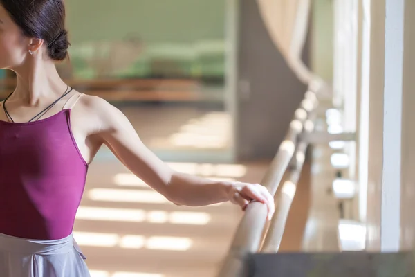 Classic ballet dancer posing at barre on rehearsal room background — Stock Photo, Image