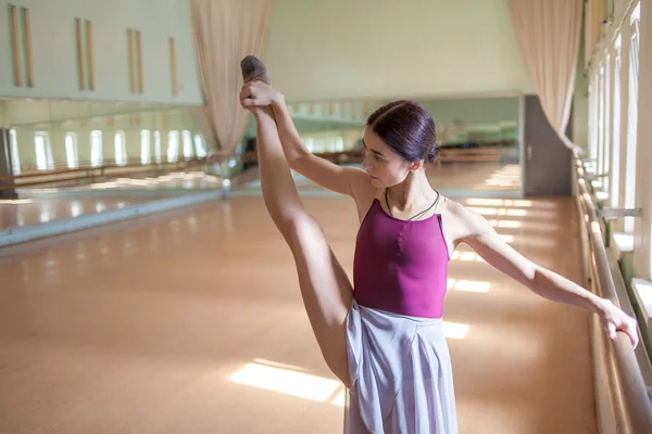 Klasyczny balet tancerz pozowanie na barre na tle sali prób — Zdjęcie stockowe