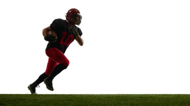 Amerikalı futbolcu, beyaz arka planda tek başına sahada topu taşıyan odaklanmış duygularla koşuyor. Atletik hareket kavramı, spor eğitimi, promosyon görselleri.