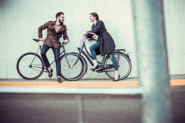 Jovem casal com uma bicicleta em frente à cidade — Fotografia de Stock