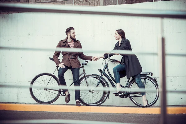 Jovem casal com uma bicicleta em frente à cidade — Fotografia de Stock