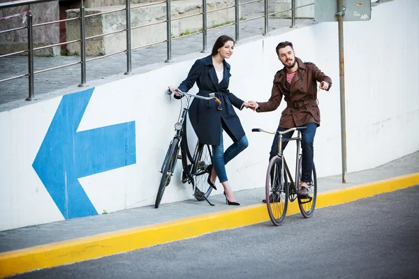 Ungt par med en cykel mittemot city — Stockfoto