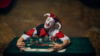 Soytarı poker masasına yaslanmış, heyecanlı yüzüyle fiş destelerini kucaklıyor. Kumarhane hikaye anlatımı, dramatik karakter davranışları, mizahi oyun senaryoları ve eğlence odaklı görseller..