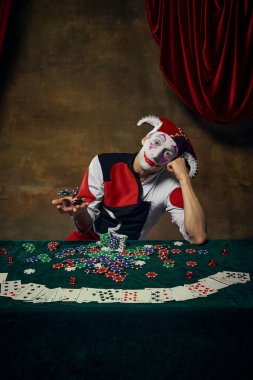 Retro soytarı, poker masasının üstünde çipleri çevirirken başını eğiyor. Kumarhane boş zamanları, eğlence karakteri çalışmaları ve oyunlarla ilgili görseller kavramı.