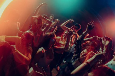 Sinematik renkli ışıklar altında dans eden neşeli kalabalık. Toplu mutluluk kavramı, duygusal ifade, gece özgürlüğü, müzik güdümlü birlik ve yeni yılı kutlama havası.