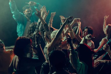 Renkli kulüp ışıkları altında ellerini kaldırmış enerjik dans kalabalığı. Yeni yıl kutlamaları, paylaşılan neşe, gece enerjisi, müzik özgürlük ve modern parti atmosferi..