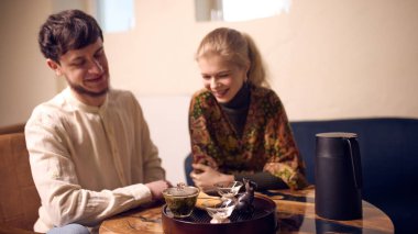 Sakin ev çayı seremonisi sırasında genç bir çift birlikte çay hazırlıyor. Yaşam tarzı blogları için ev çayı hazırlama kavramı, içecek reklamları, sosyal medya içeriği ve sakin günlük rutin görseller.