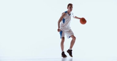 Basketbolcu stüdyo ortamında düşük kontrollü dribble yapıyor. Yetenek geliştirme, hareket analizi, spor tekniği eğitimi ve odaklanmış atletik oturumlar kavramı.