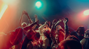 Gece müzik etkinliği sırasında etkileyici kalabalık hareketi. Duygusal yoğunluk, paylaşılan deneyim, ritmik özgürlük, engebeli ses manzarası ve Noel partisi atmosferi kavramı.