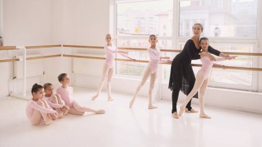 Dans stüdyosunda denge egzersizi sırasında öğrencilere yardımcı olan bale öğretmeni. Bale eğitimi reklamı, dans eğitimi tanıtımı, profesyonel koçluk pazarlaması ve stüdyo markalaşma içeriği kavramı