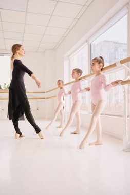 Stüdyo barındaki genç dansçıların duruşunu düzelten bale öğretmeni. Yapılandırılmış bale öğrenme süreci, organize eğitim programları ve eğitim sunumu içeriği kavramı.