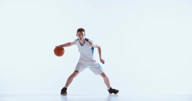 Basketbolcu, topa doğru hareketli bir şekilde bakıyor. Atletik hazırlık kavramı, gençlik sporu görselleri, profesyonel eğitim tasvirleri ve kontrollü teknik çalışmaları.