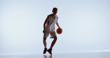 Odaklanmış basketbolcu düşük duruşta hızlı top sürüyor. Hız kontrolü, taktik ayak hakimiyeti, oyun hazırlığı ve yoğun atletik disiplin kavramı..