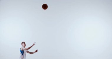 Basketbolcu yukarıdan atlıyor, yukarıdan düşen top için uzanıyor. Tepki eğitimi, refleks geliştirme, spor koçluğu ve atletik hareket eğitimi kavramı.