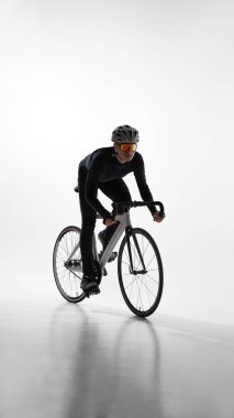 Bisikletçi beyaz arka planda, yan manzarada bisiklet sürüyor. Hareket analizi, bisiklet tekniği, dayanıklılık sporu ve profesyonel atlet yaşam tarzı kavramı.