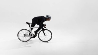 Stüdyoda bisikletle yarışan profesyonel bisikletçilerin yan görüntüsü. Hız eğitimi, bisiklet yarışması, dayanıklılık sporu, atletik performans, minimum stüdyo ortamı.