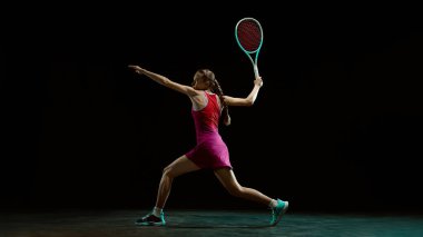 Hareket halindeki bayan tenisçi stüdyoda kontrollü ters vuruş yapıyor. Teknik, kontrol, atletik disiplin, kaliteli spor markalaşması ve rekabetçi eğitim ortamı kavramı.