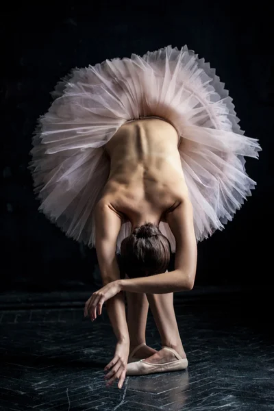 Hermosa bailarina posando apoyada en dack fondo — Foto de Stock